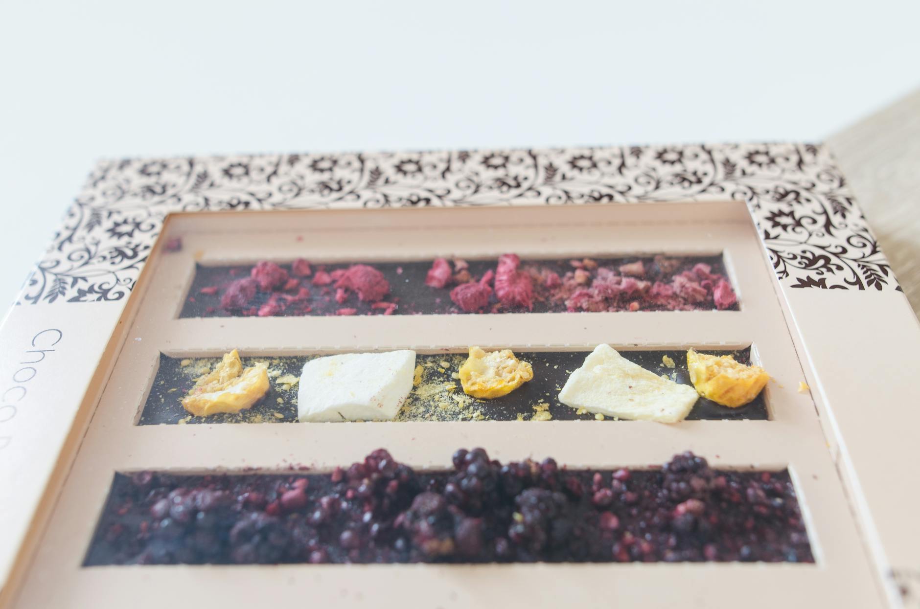 Ultimate Chocolate and Nuts: Best Indulgence A close-up of an artisanal chocolate bar with dried fruits and nuts in a decorative box.