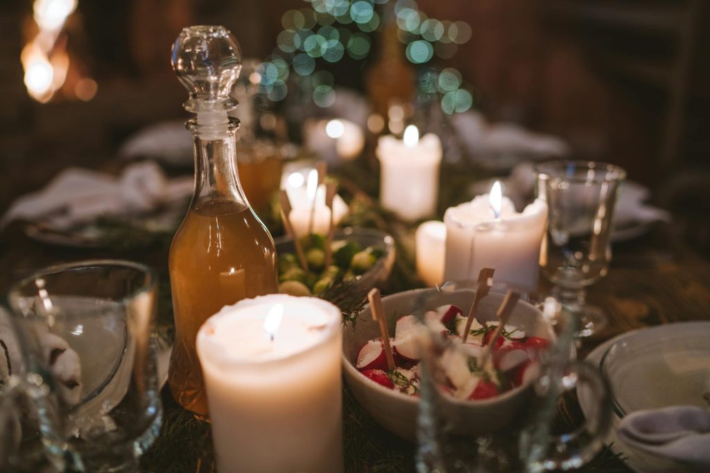 Warm candlelit table setting with a cozy holiday atmosphere featuring food, drinks, and decor.