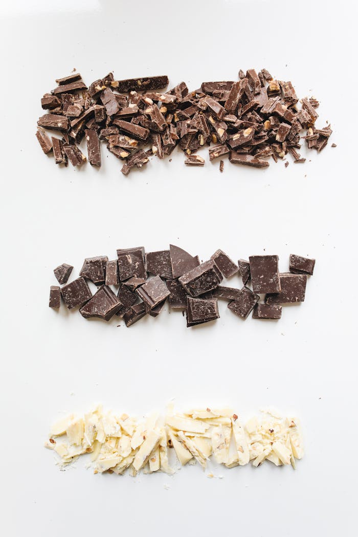 services-03 Flat lay of assorted milk, dark, and white chocolate pieces on a white background.
