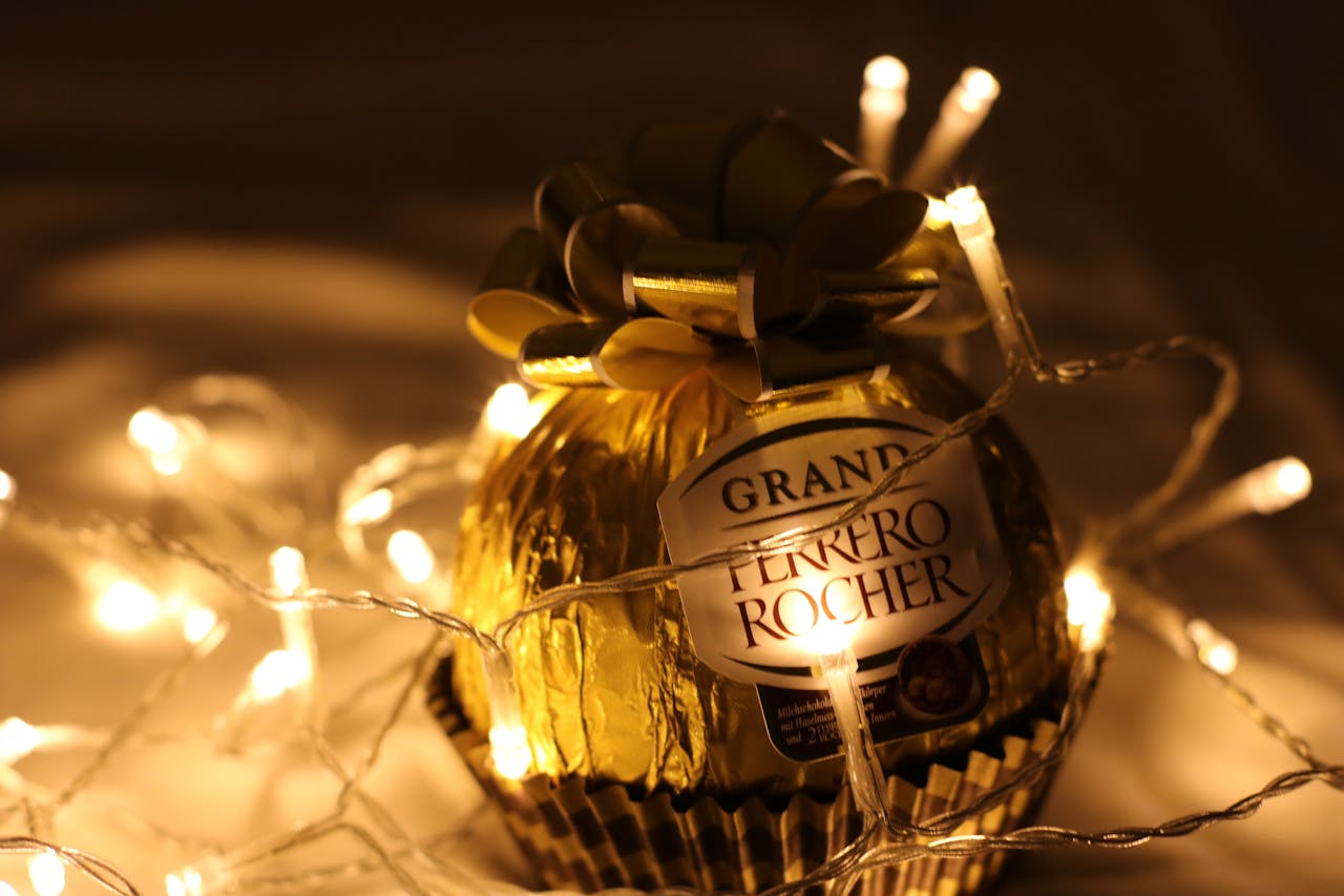 about-02 A Grand Ferrero Rocher chocolate illuminated by warm LED string lights, perfect for Christmas decor.